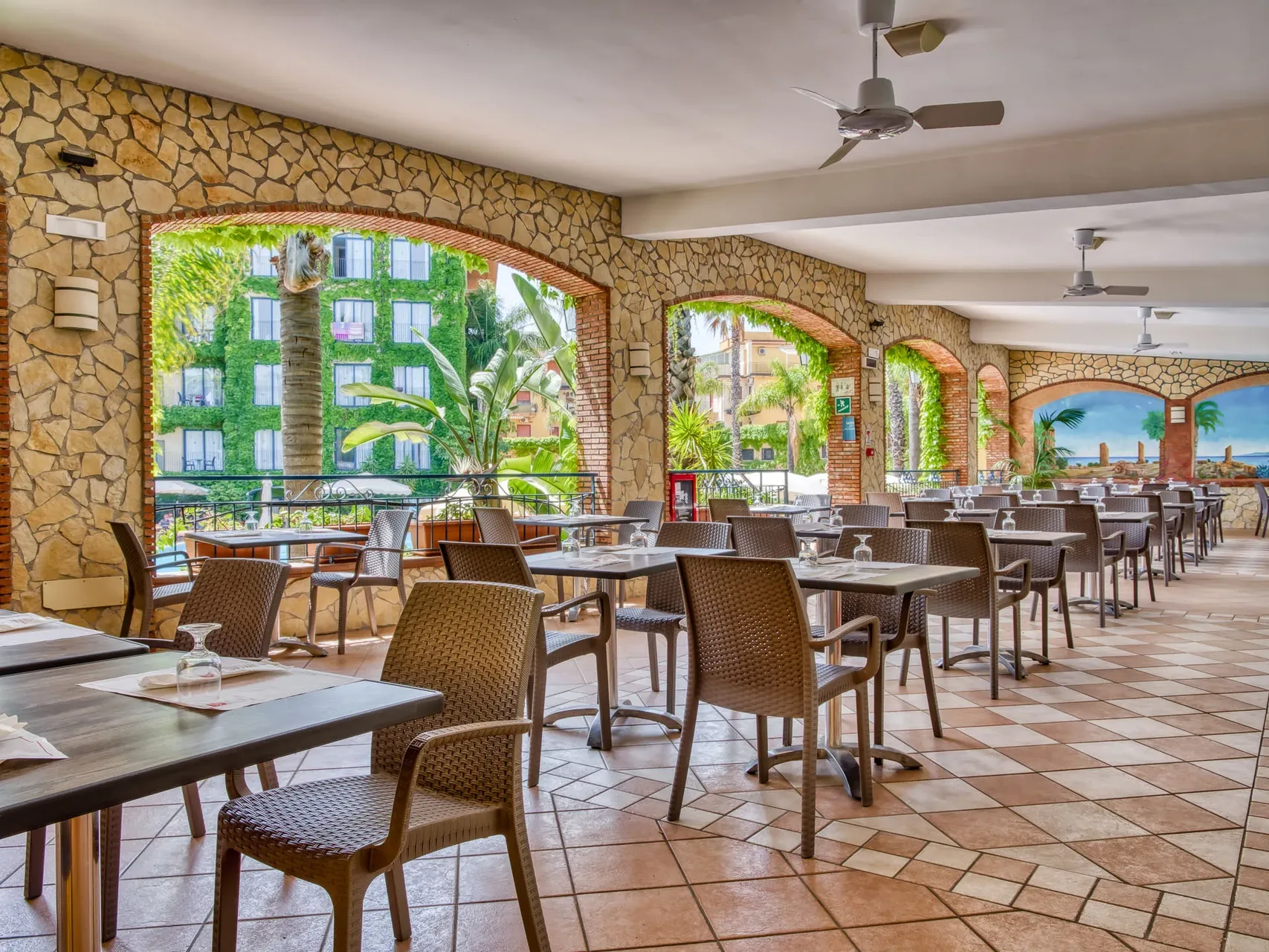 Terrazza ristorante con archi in pietra, tavoli e sedie affacciata sul giardino