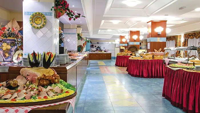 Sala buffet dell'hotel con piatti caldi e freddi disposti su tavoli con tovaglie rosse