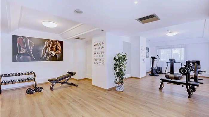 Sala fitness con pesi liberi, panche e attrezzature per l'allenamento su pavimento in legno