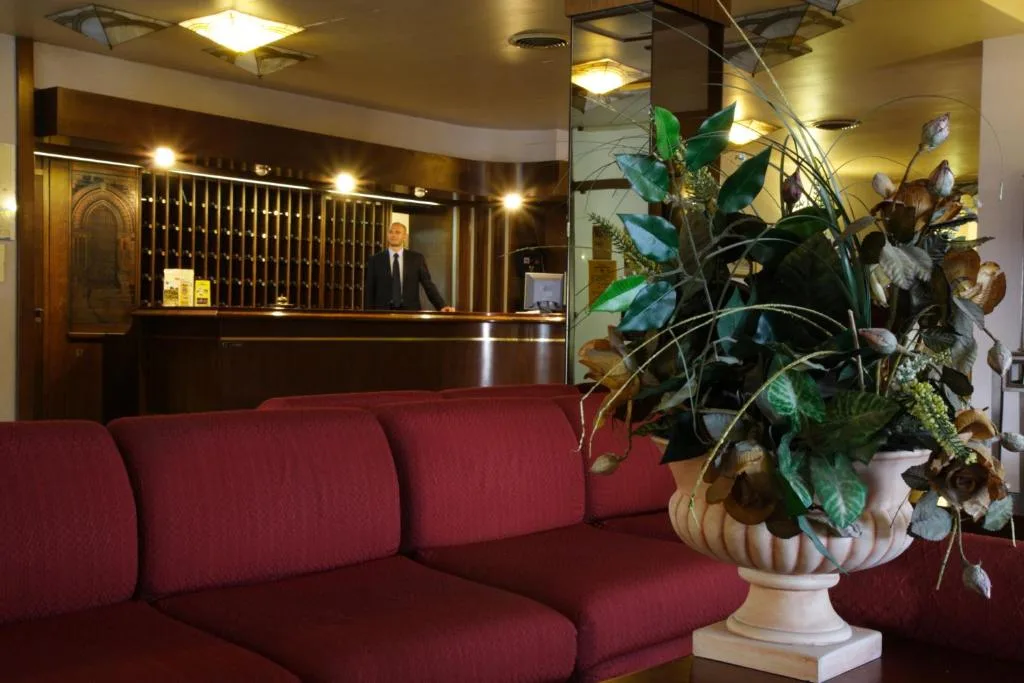 Hall dell'hotel con reception in legno, divano rosso e composizione floreale
