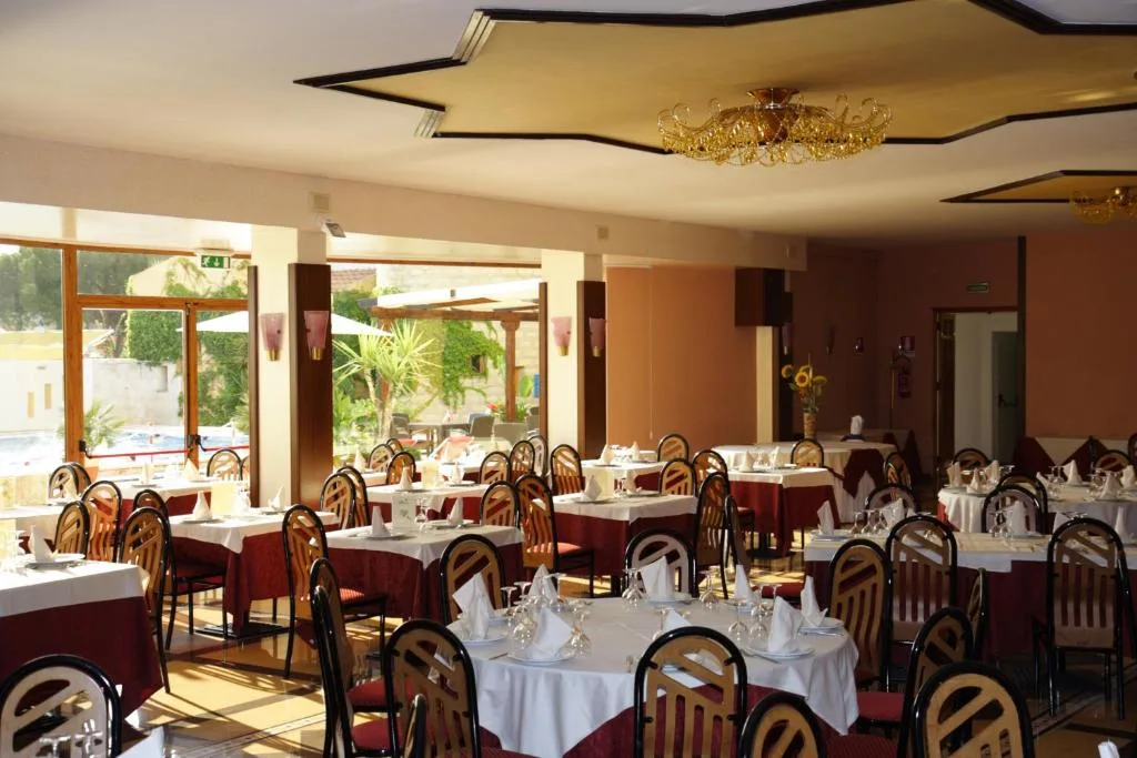 Sala ristorante con tavoli apparecchiati e grandi finestre con vista sul giardino