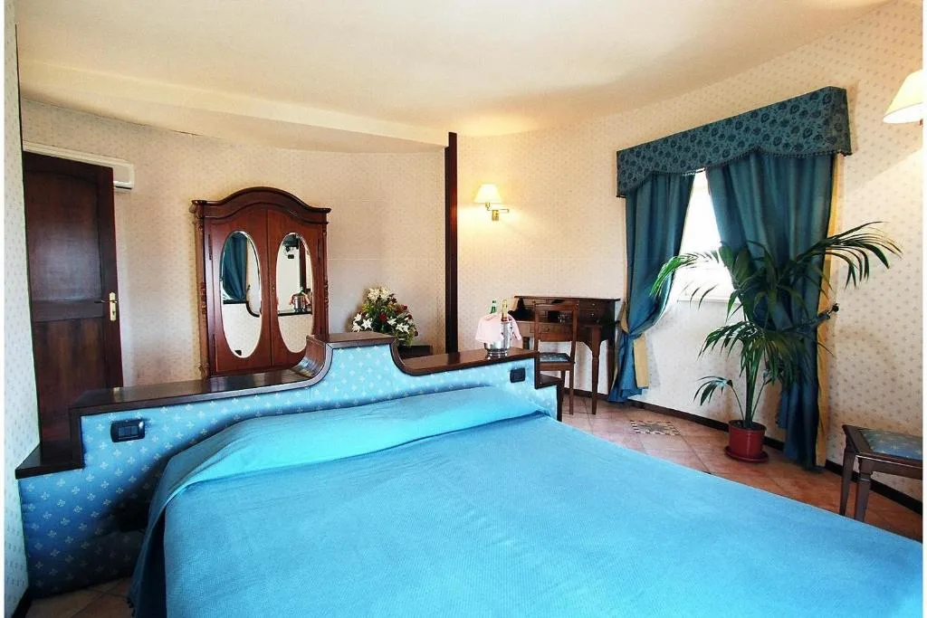 Camera con letto matrimoniale, copriletto azzurro, armadio in legno e scrivania