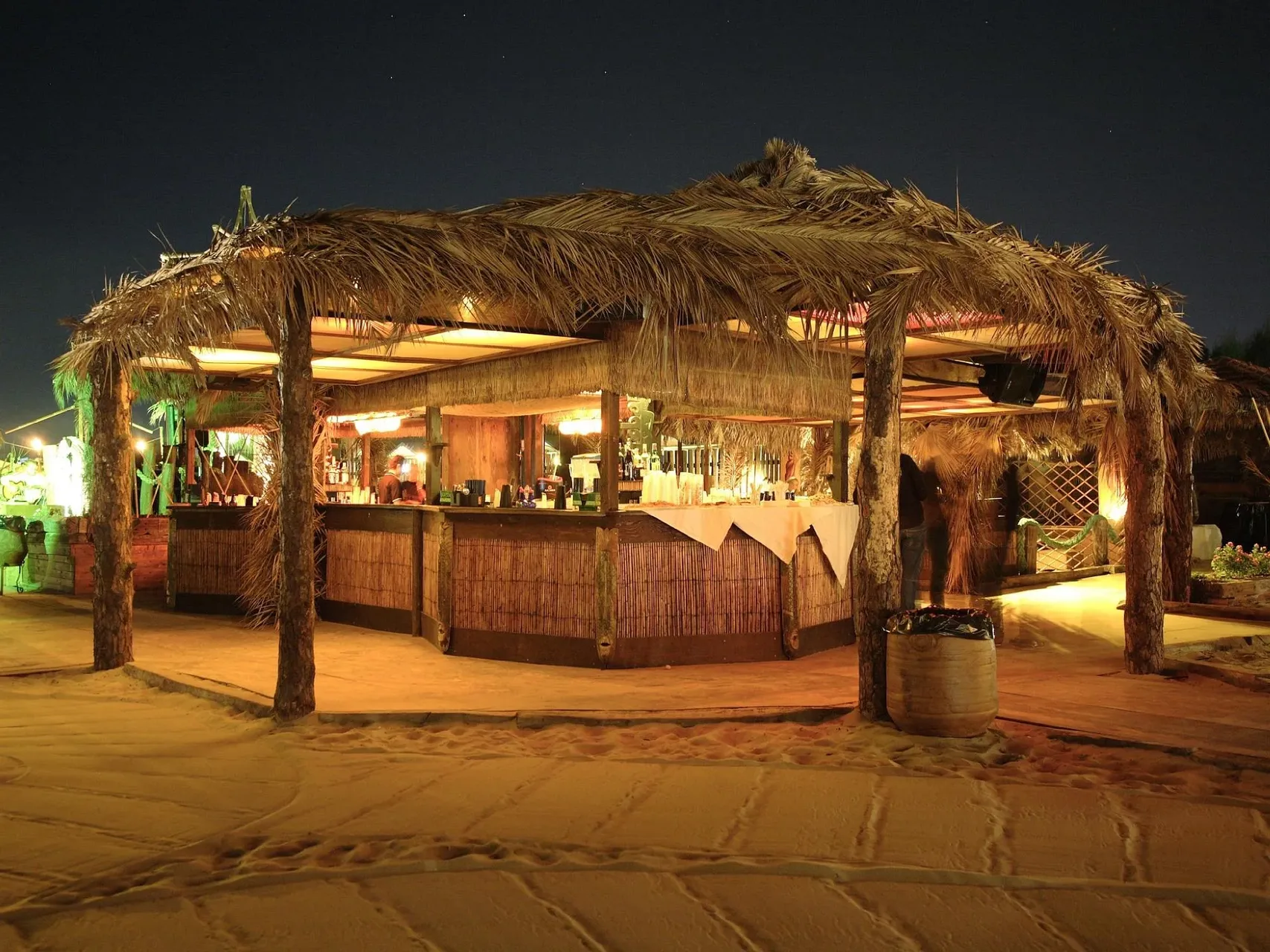 Bar sulla spiaggia con tetto in paglia illuminato di sera