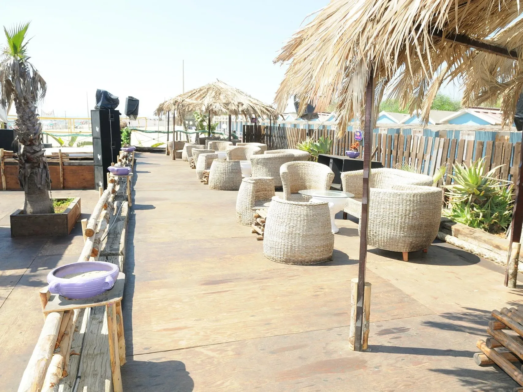 Area lounge con poltrone in vimini e ombrelloni in paglia sulla spiaggia