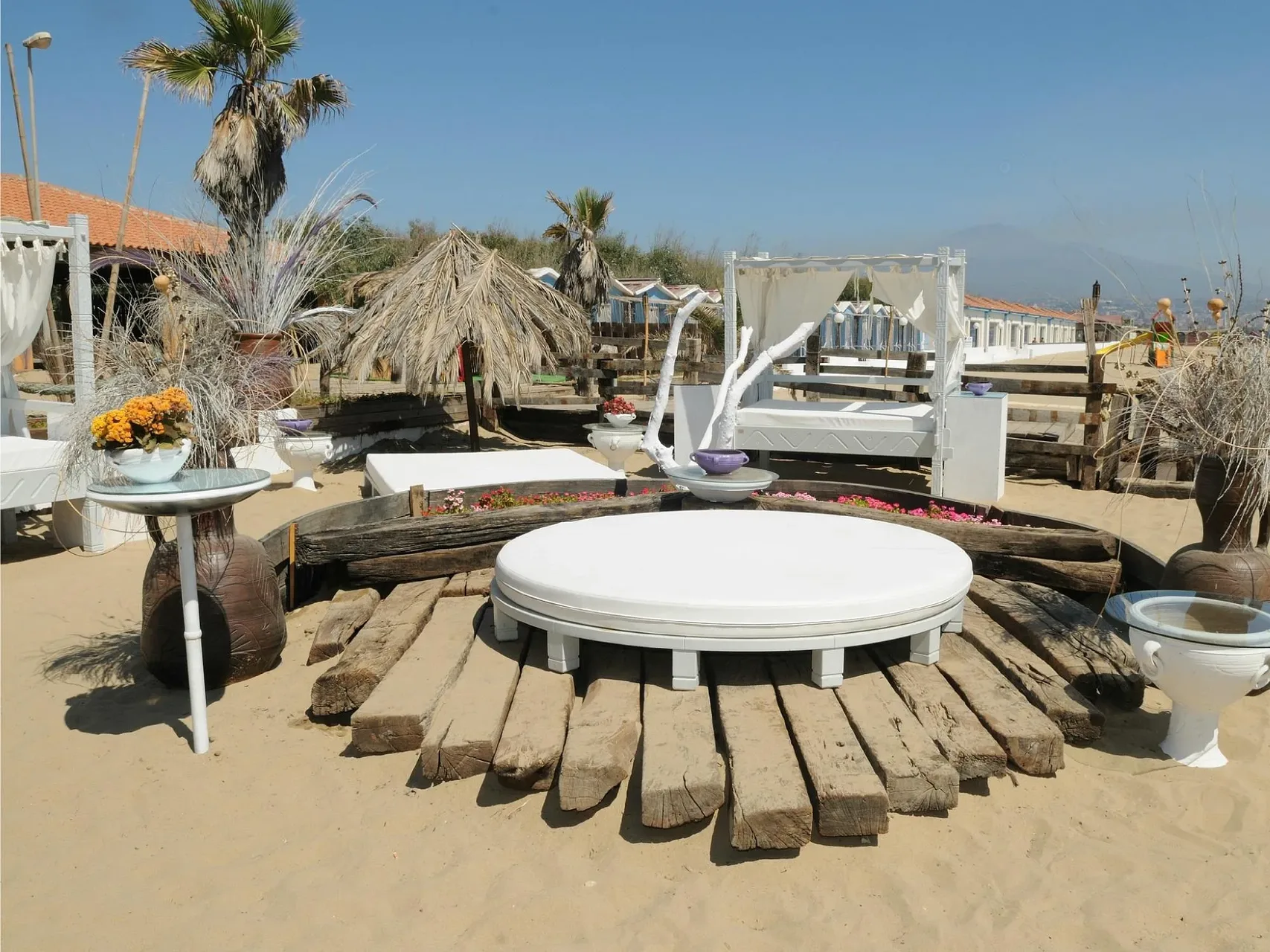 Zona relax sulla spiaggia con lettini bianchi e decorazioni floreali