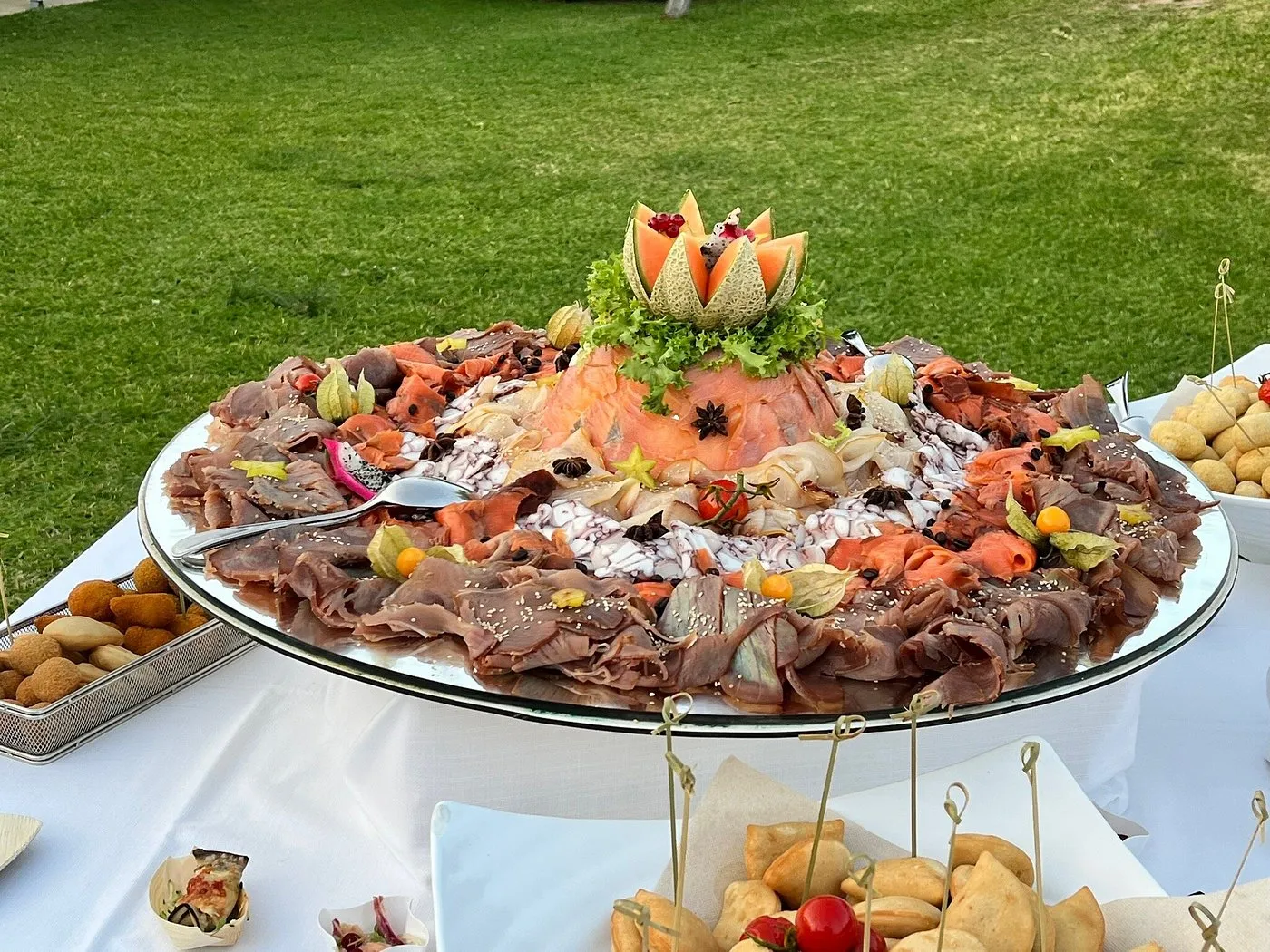 Vassoio di affettati e salumi decorato con melone su buffet all'aperto