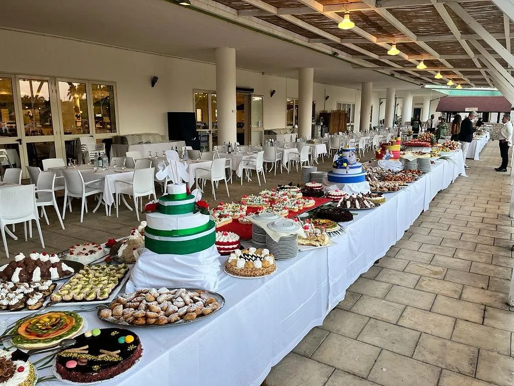 Lungo buffet di dolci e torte allestito su tavolo bianco al coperto