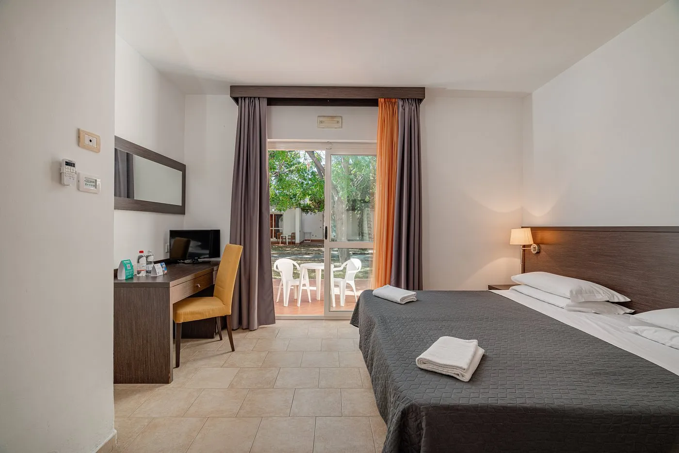 Camera luminosa con letto matrimoniale, scrivania e uscita sul giardino