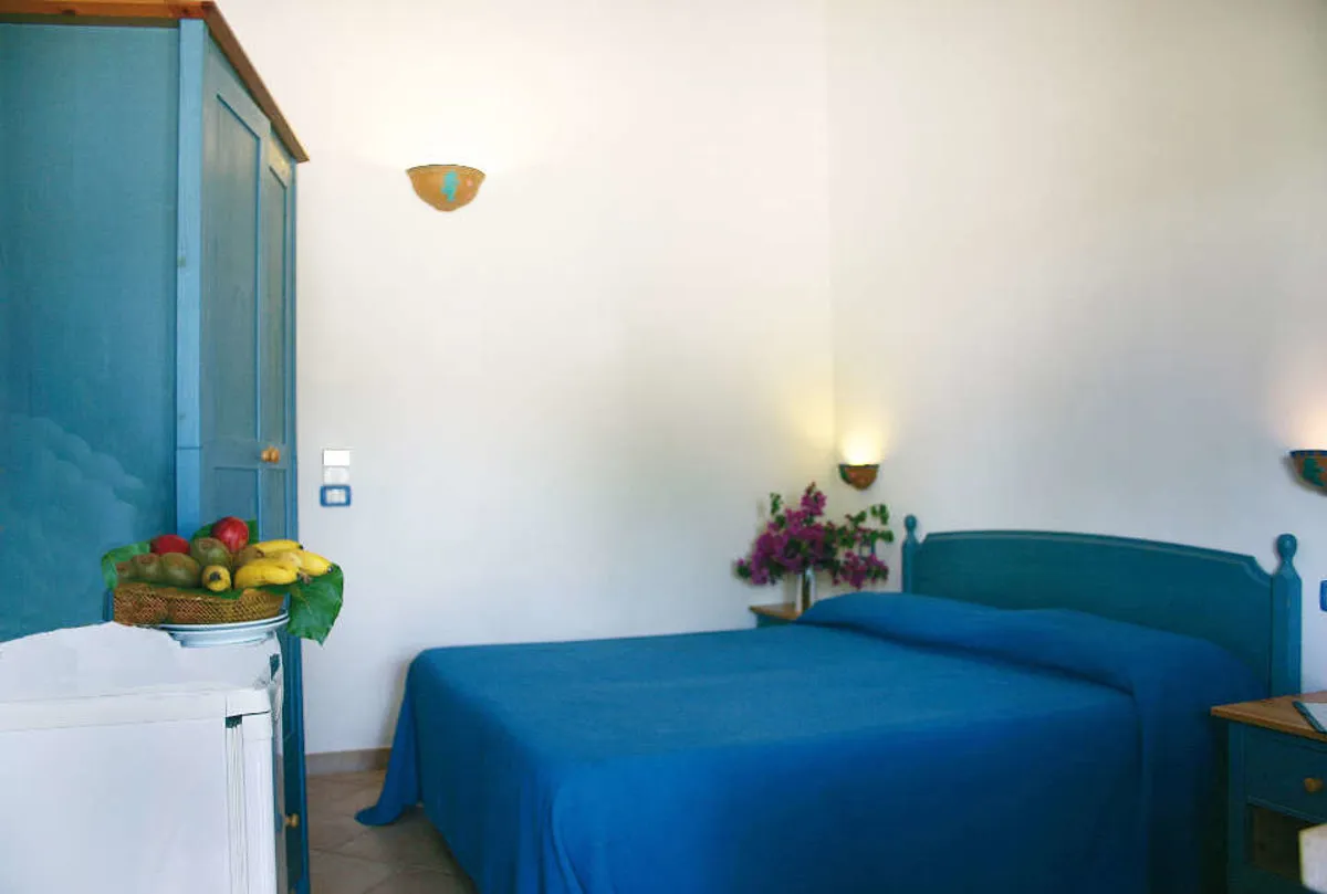 Camera da letto matrimoniale con arredi blu e cesto di frutta