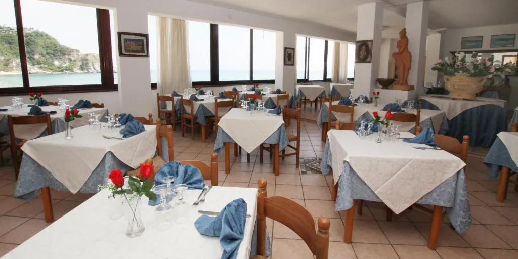 Sala ristorante interna con tavoli apparecchiati e ampie finestre vista mare
