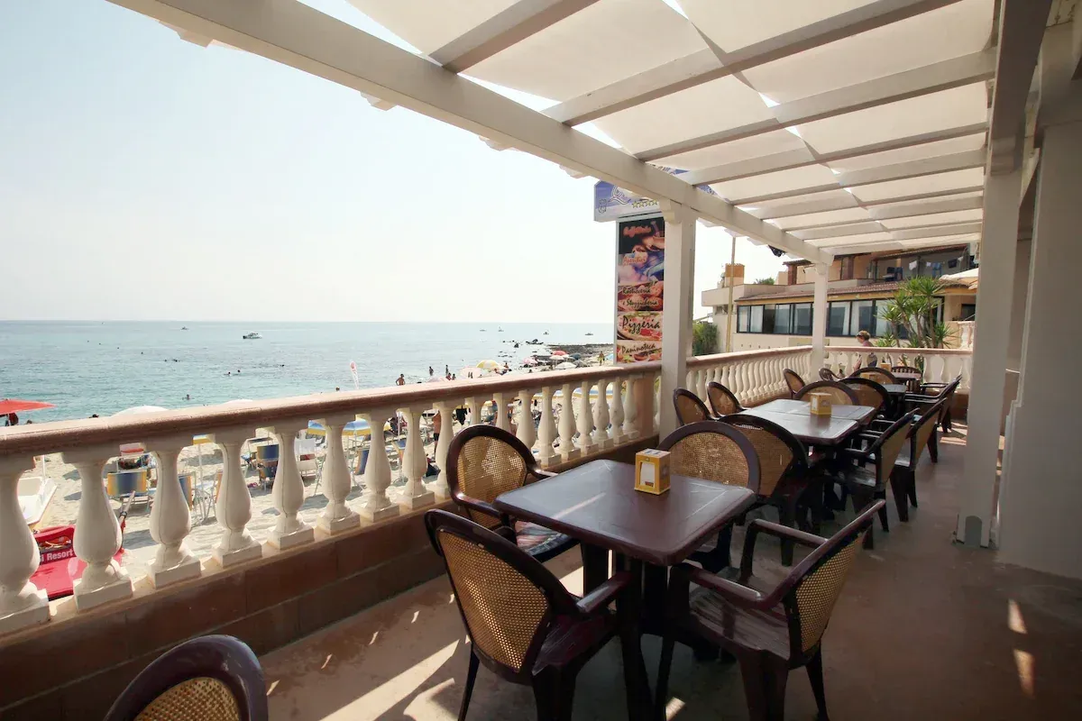 Terrazza coperta con tavoli e sedie affacciata sulla spiaggia e sul mare