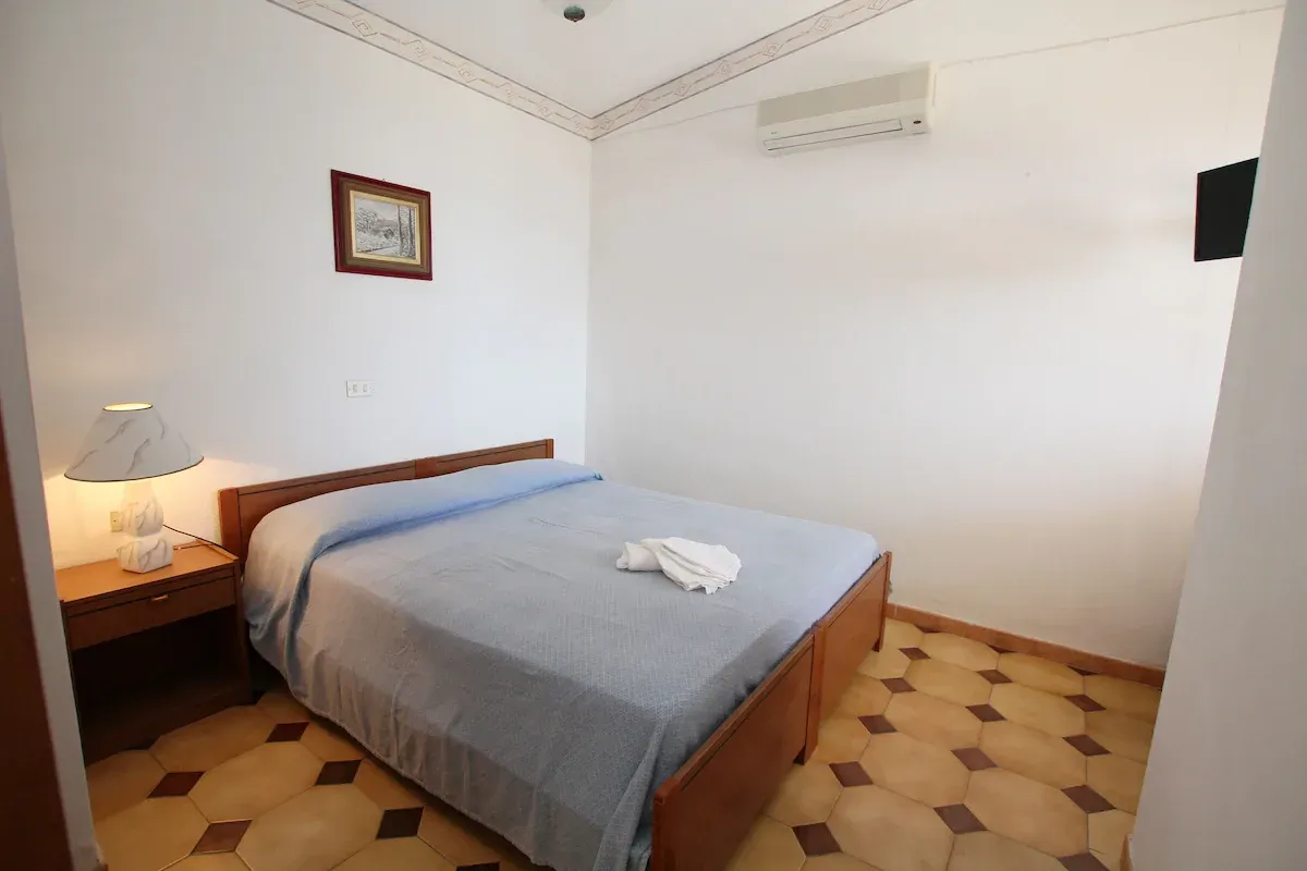 Camera matrimoniale semplice con letto, comodino e aria condizionata