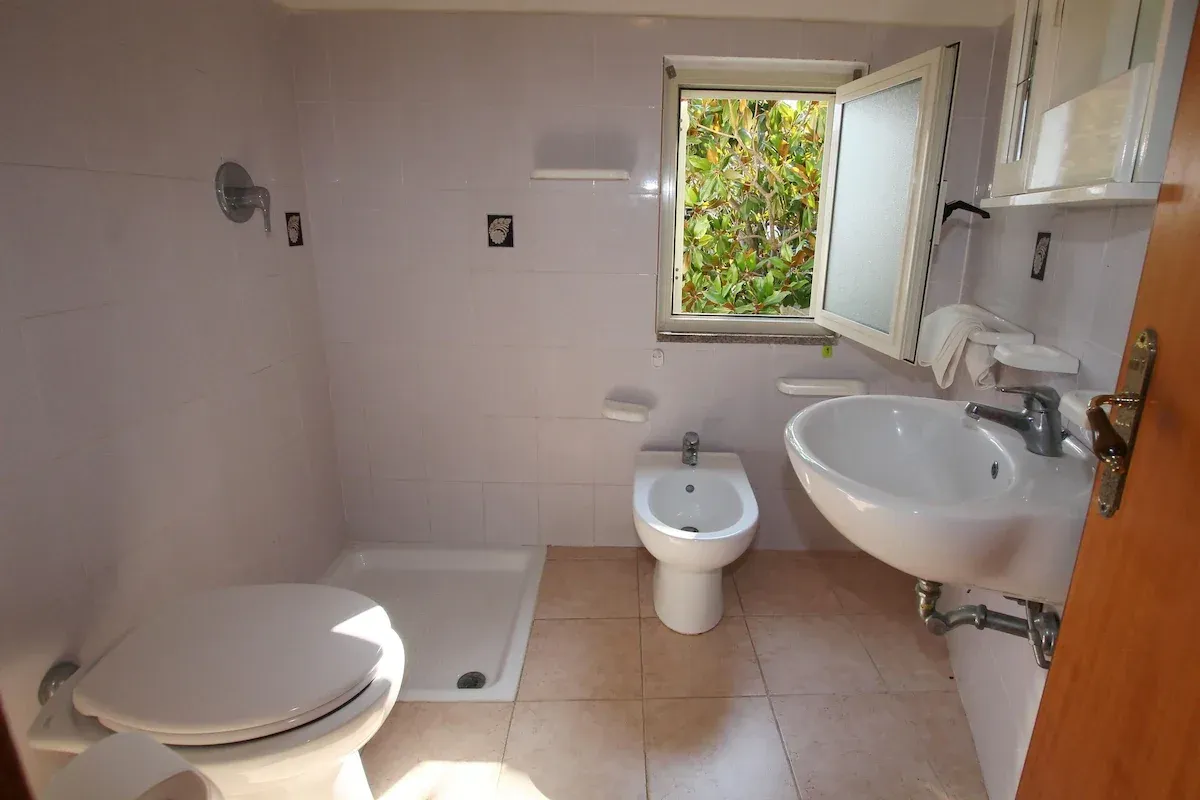 Bagno con doccia, bidet, WC e lavabo con finestra sulla vegetazione