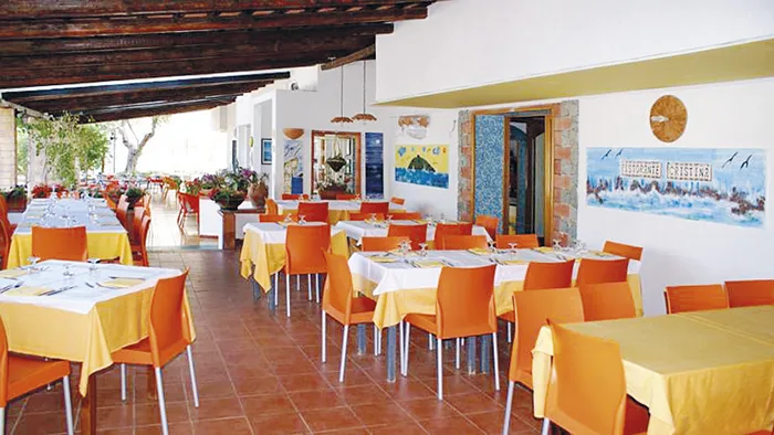 Sala ristorante coperta con tavoli e sedie arancioni e decorazioni alle pareti