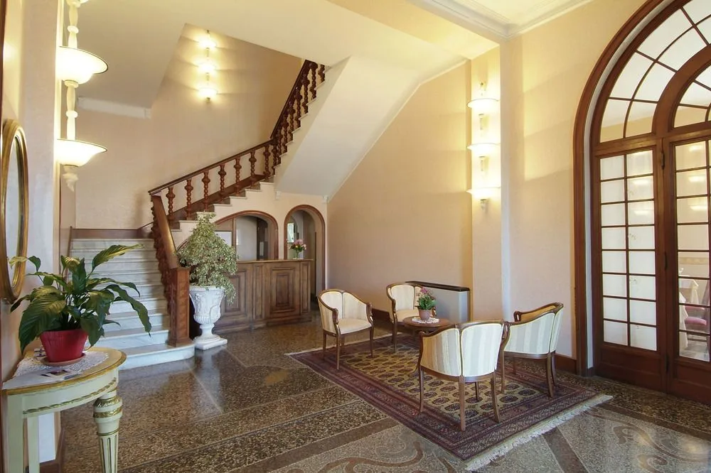 Elegante hall con scalinata in legno, poltrone e pavimento decorato