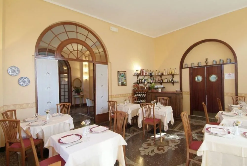 Sala ristorante con tavoli apparecchiati, archi in legno e pavimento decorato