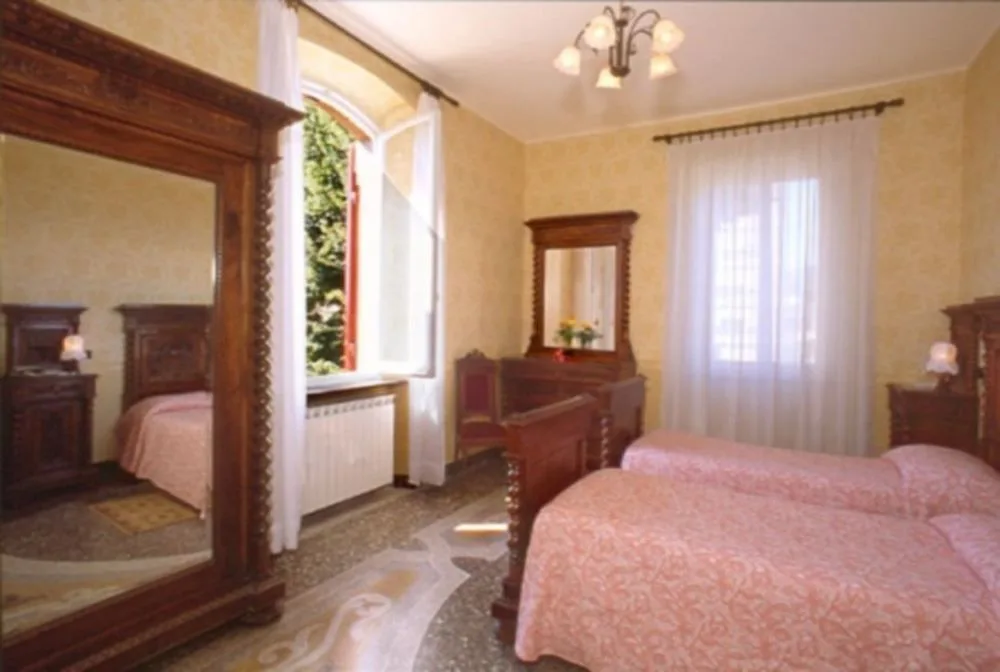 Camera con letti singoli rosa, mobili antichi in legno e finestra affacciata sul verde