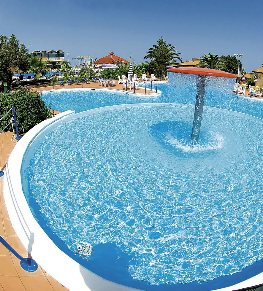 Piscina rotonda per bambini con fontana a cascata e ombrelloni sullo sfondo