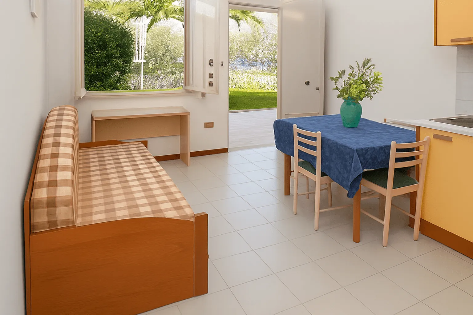 Soggiorno luminoso con angolo cottura, tavolo da pranzo e divano con uscita sul giardino