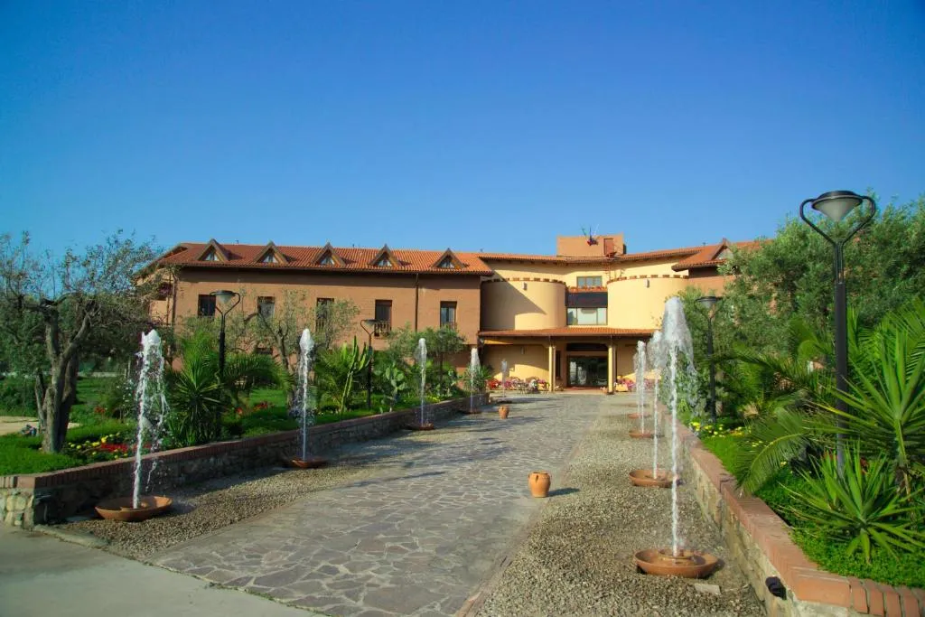 Ingresso dell'hotel con viale di fontane zampillanti e giardino curato