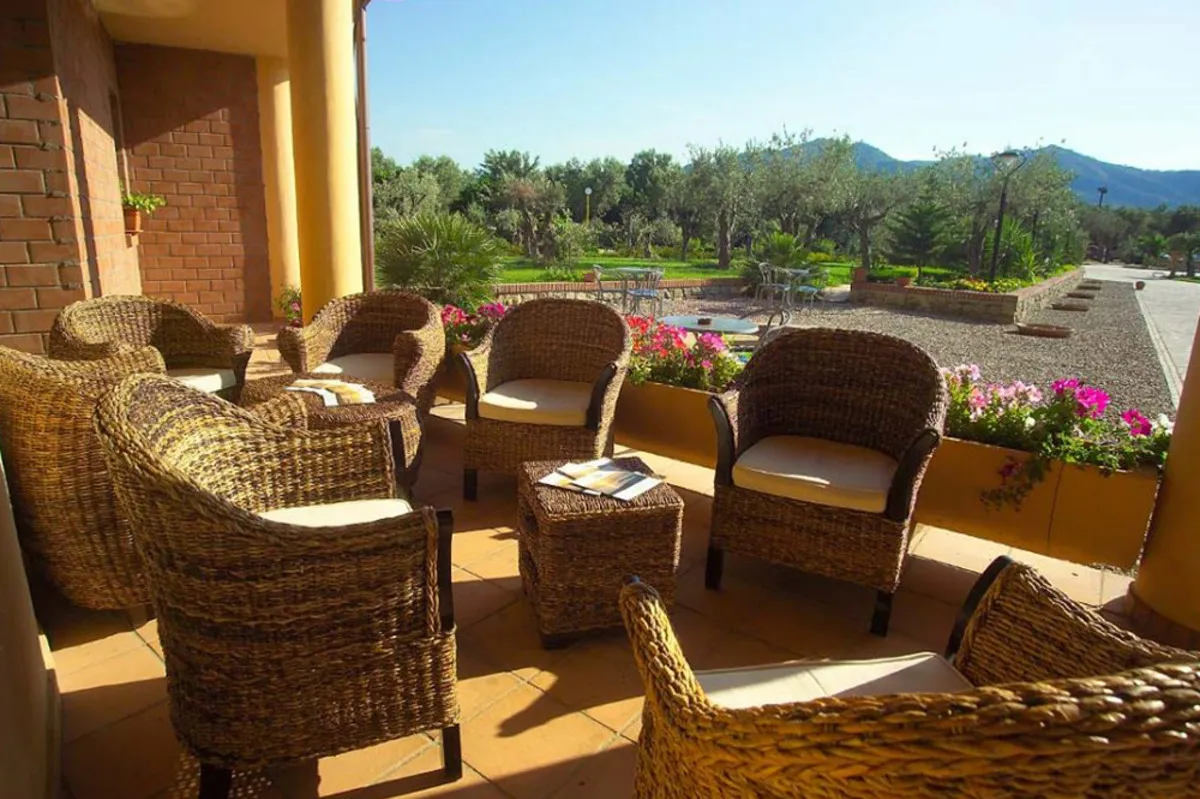 Terrazza con poltrone in vimini e vista sul giardino fiorito e le colline