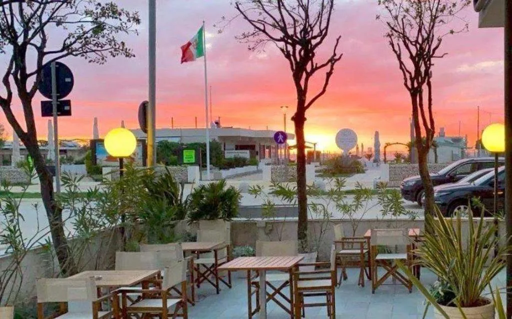 Terrazza dell'hotel con tavolini al tramonto e cielo rosato