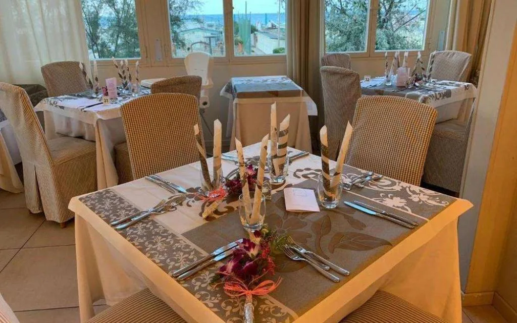 Sala ristorante con tavoli apparecchiati e vista mare