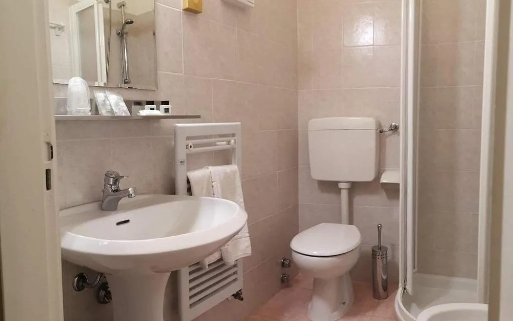 Bagno con lavabo, WC e box doccia in piastrelle chiare