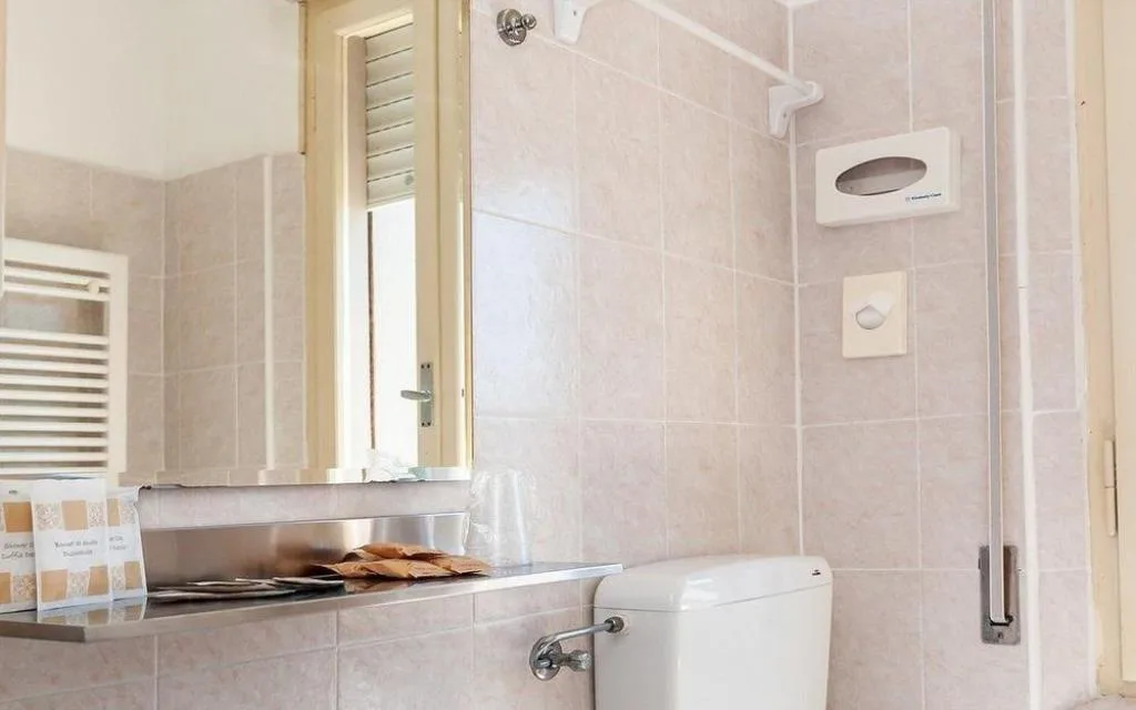 Bagno con specchio, finestra e piastrelle beige