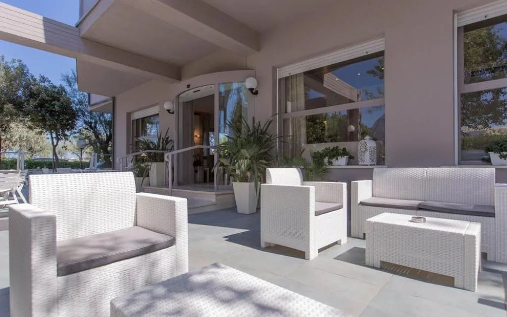 Terrazza esterna con divani in rattan bianco e ingresso a vetri