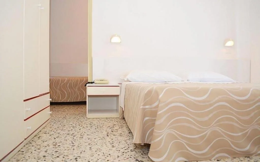 Camera con letto matrimoniale, armadio e pavimento in graniglia