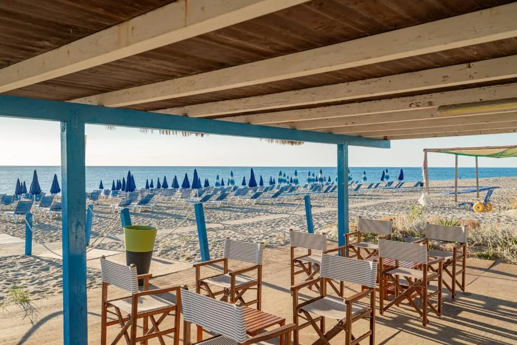 Area relax in spiaggia con tavoli e sedie sotto pergola e vista mare