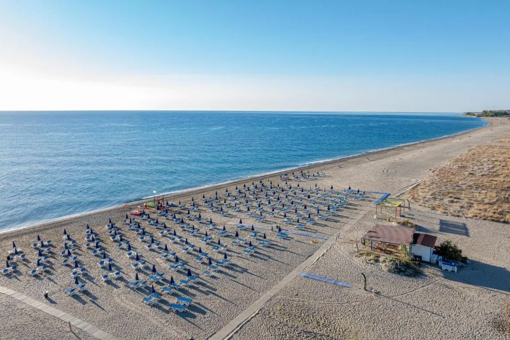 Veduta aerea della spiaggia con lettini, ombrelloni blu e mare calmo