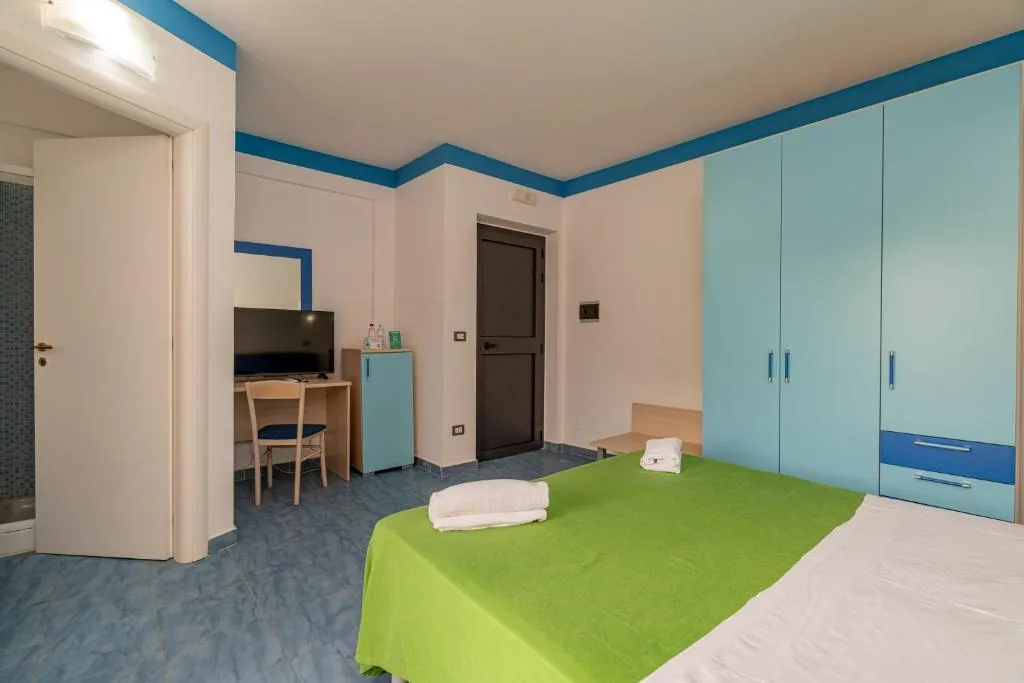 Camera con letto, armadio azzurro, scrivania e TV