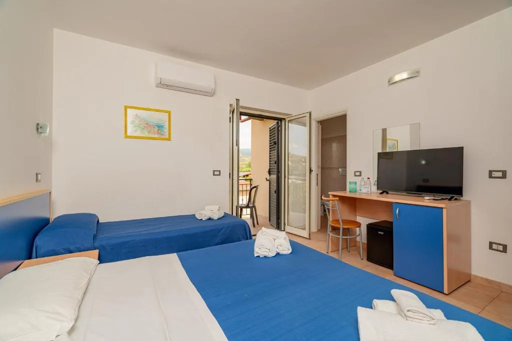 Camera doppia con letti blu, scrivania, TV e balcone