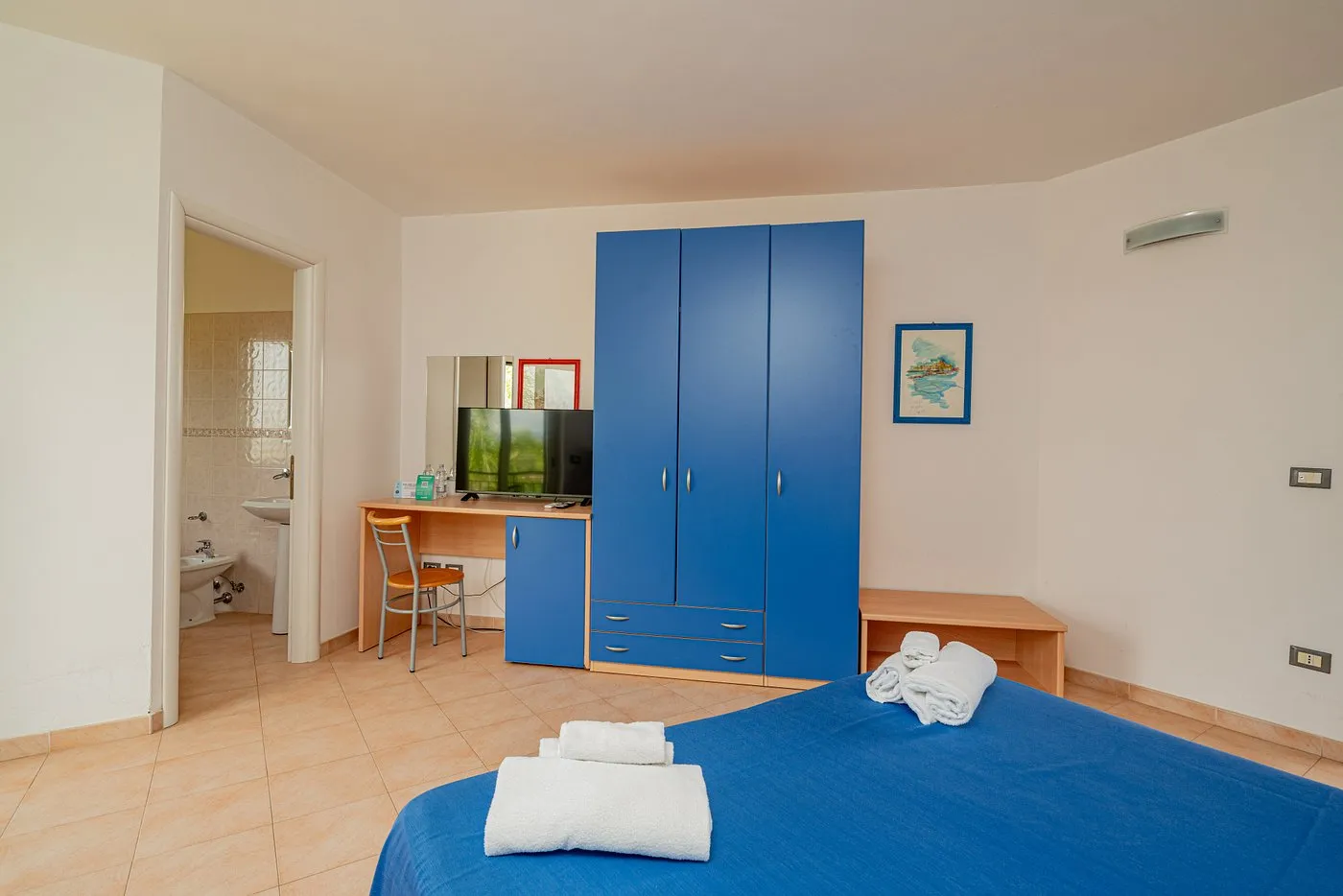 Spaziosa camera matrimoniale con armadio blu, scrivania e bagno privato