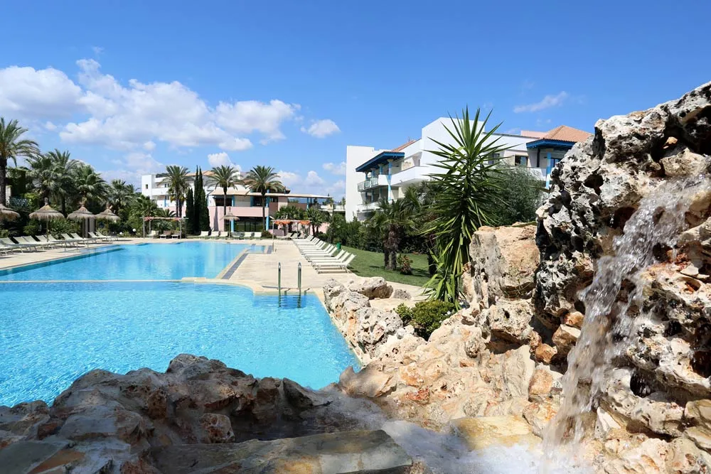 Piscina con cascata rocciosa e vegetazione tropicale in primo piano