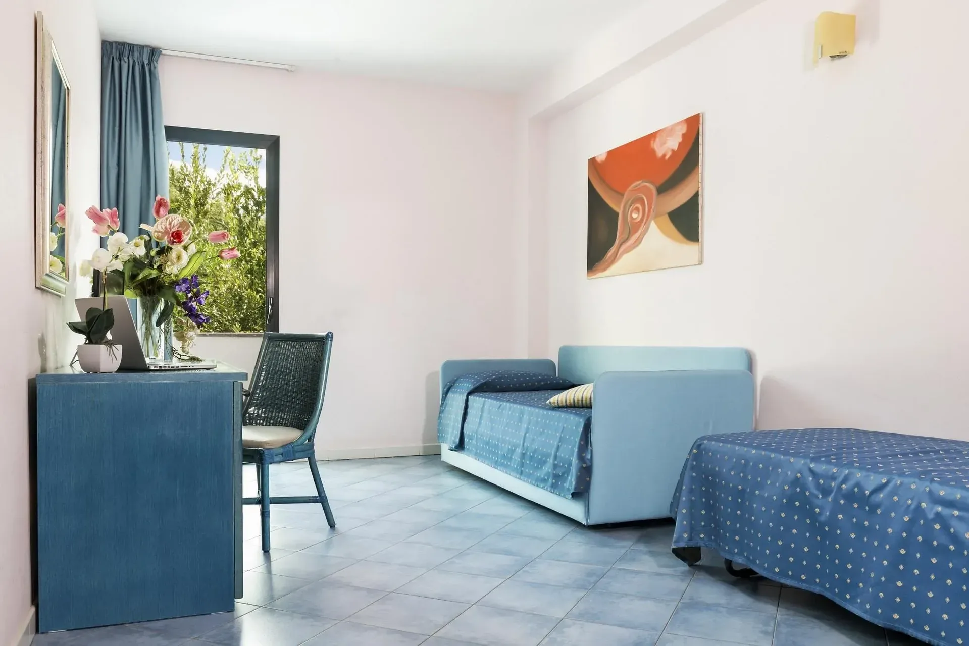 Soggiorno della camera con divano letto, scrivania e pavimento in ceramica azzurra