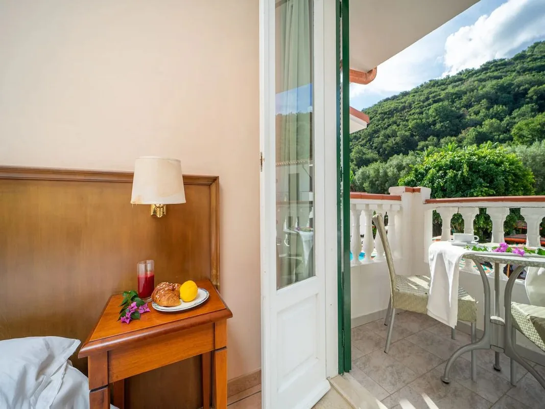 Dettaglio di comodino con colazione e balcone con tavolino affacciato sulla collina verde