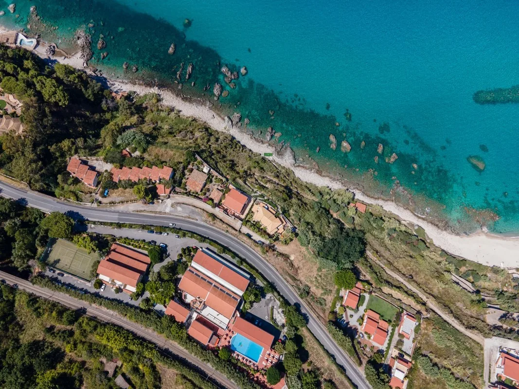 Veduta aerea dall'alto dell'hotel con piscina, strada costiera e mare turchese