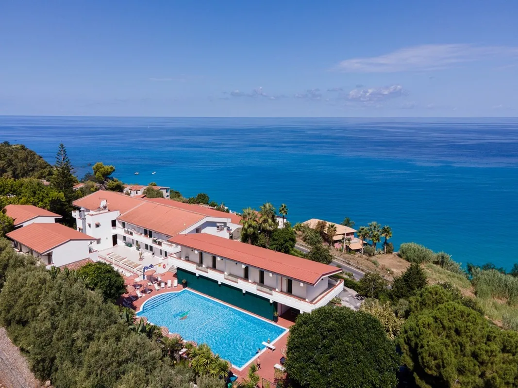 Veduta aerea dell'hotel con piscina esterna affacciato sul mare blu