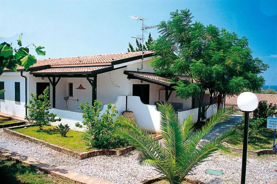 Villetta bianca con tetto in tegole, veranda e giardino con palme