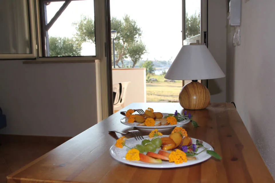 Tavolo con piatti di frutta decorata e lampada davanti alla finestra vista giardino