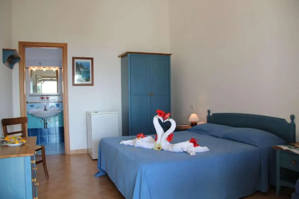 Camera matrimoniale con copriletto blu, decorazione a cigni e bagno attiguo