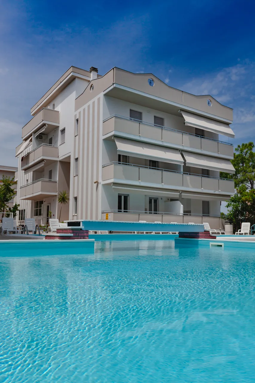 Edificio dell'hotel con balconi bianchi riflesso nell'acqua della piscina