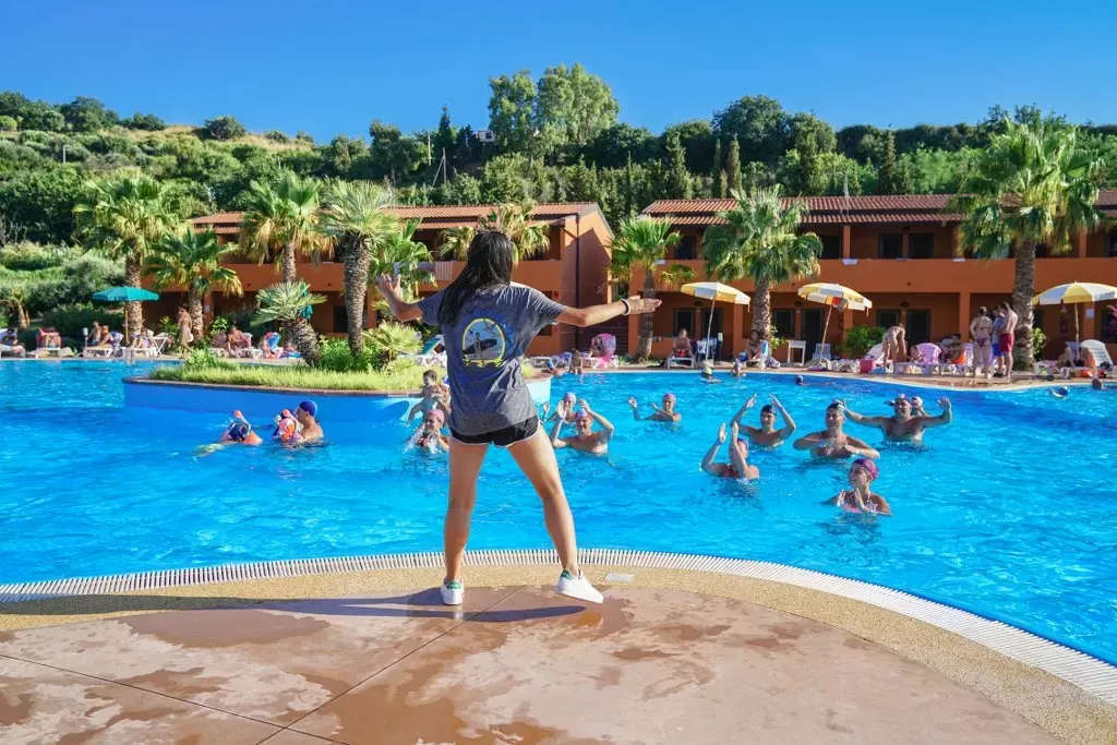 Istruttrice guida una lezione di acquagym nella piscina del resort con ospiti in acqua