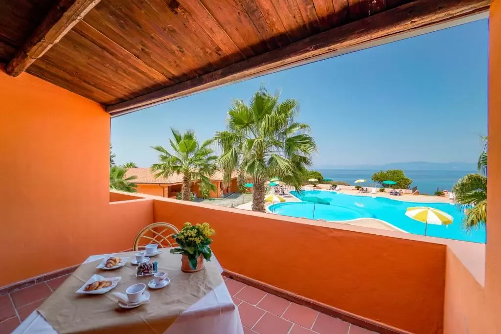 Terrazza con tavolo apparecchiato per la colazione e vista sulla piscina e sul mare