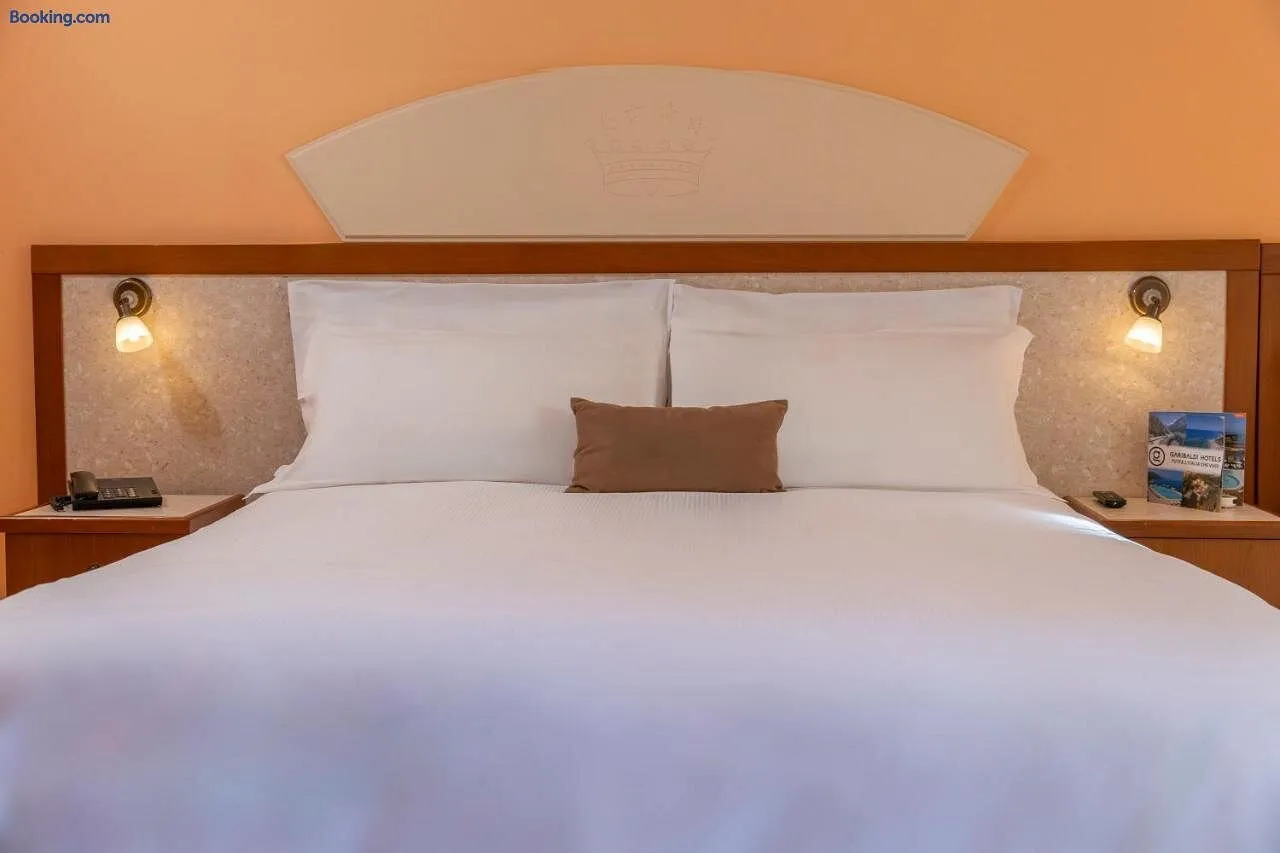 Letto matrimoniale con biancheria bianca, cuscino marrone e lampade da lettura