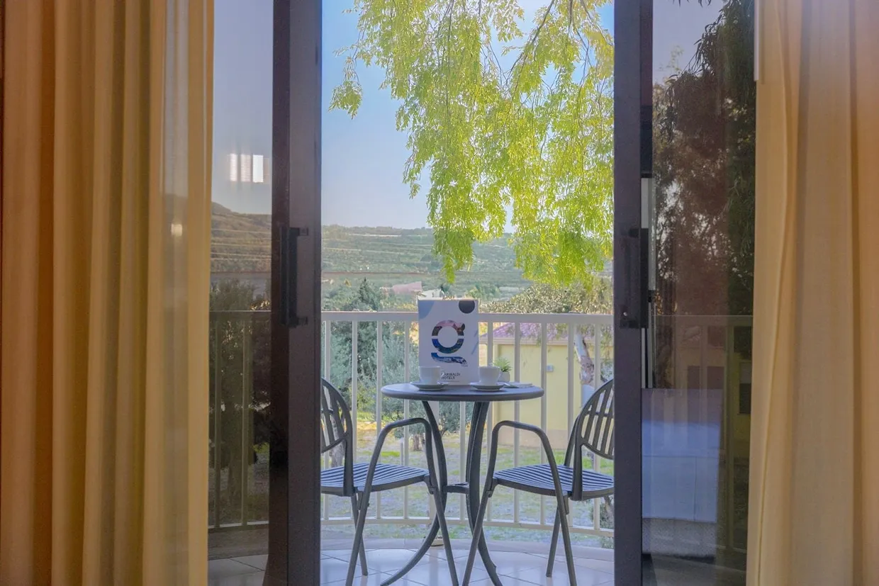 Vista dal balcone con tavolino, sedie e panorama su colline e vegetazione