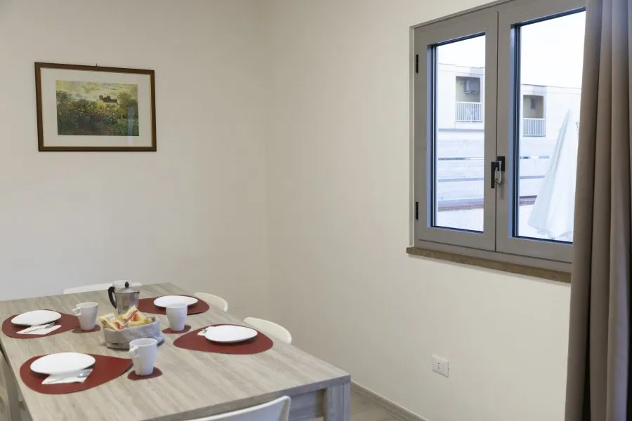 Angolo pranzo con tavolo apparecchiato, quadro a parete e finestra